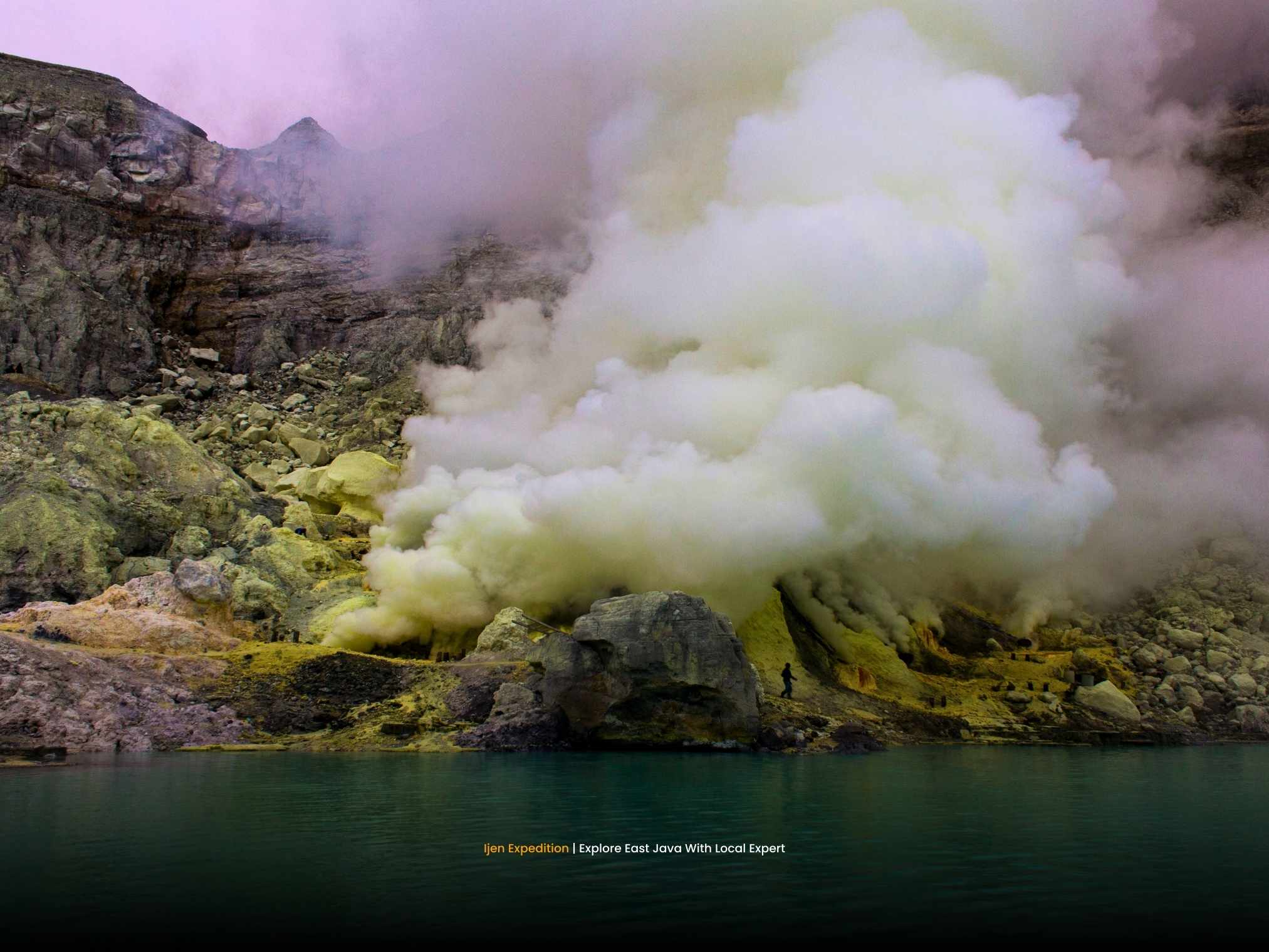Turquoise crater lake at Mount Ijen during sunrise