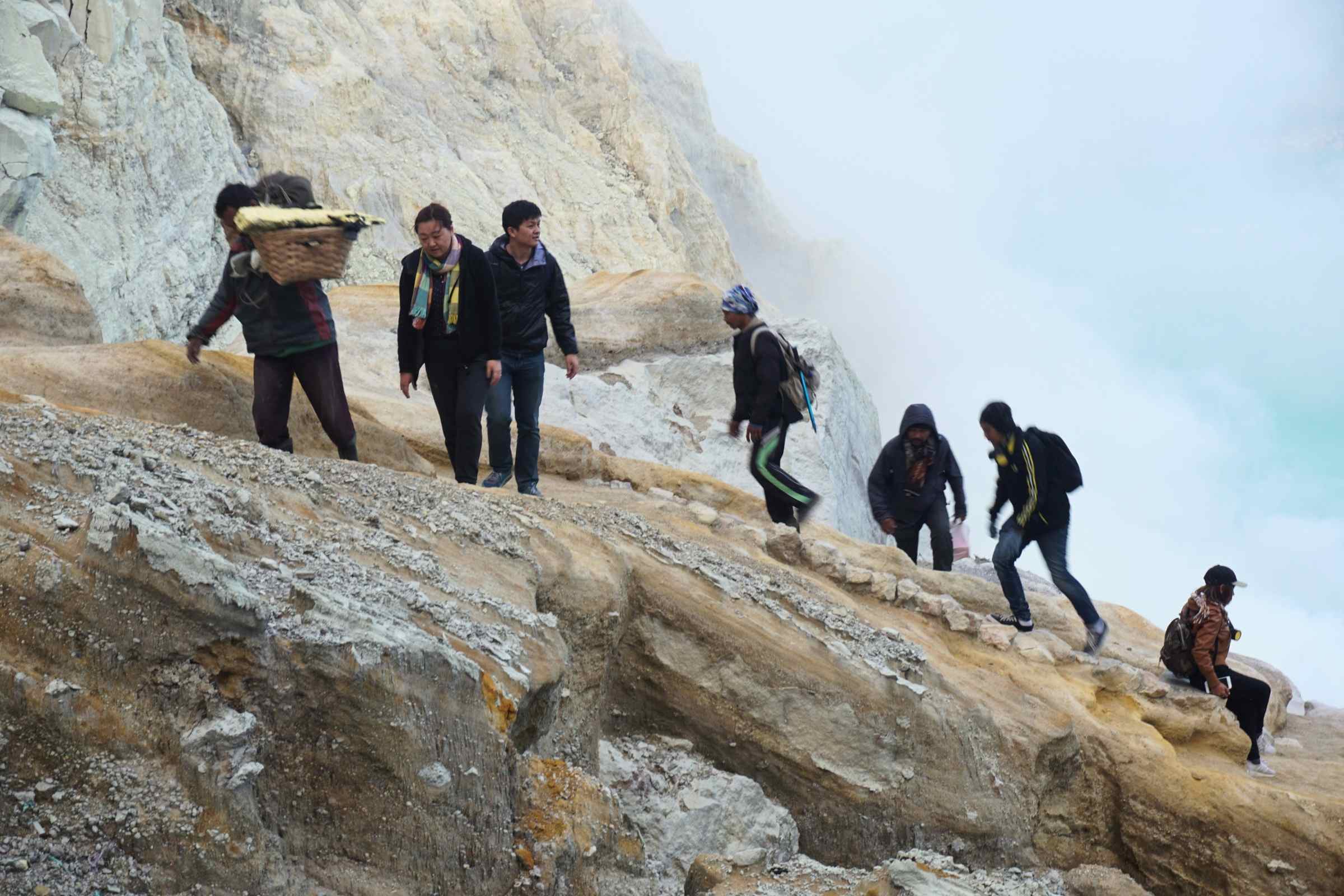 Travelers hiking Mount Ijen crater during volcano tour